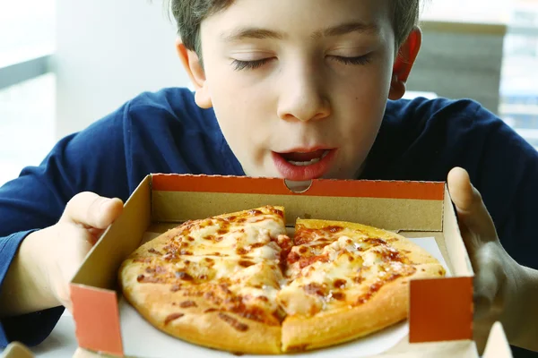 Preteen schöner Junge riecht Pizza in Box — Stockfoto