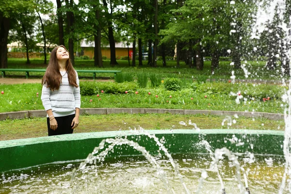 Elég tini lány néz szökőkút a parkban — Stock Fotó