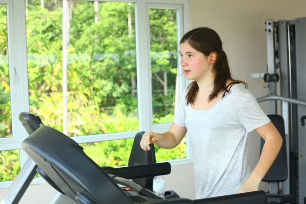 teen girl with pony tail jogging on treadmill