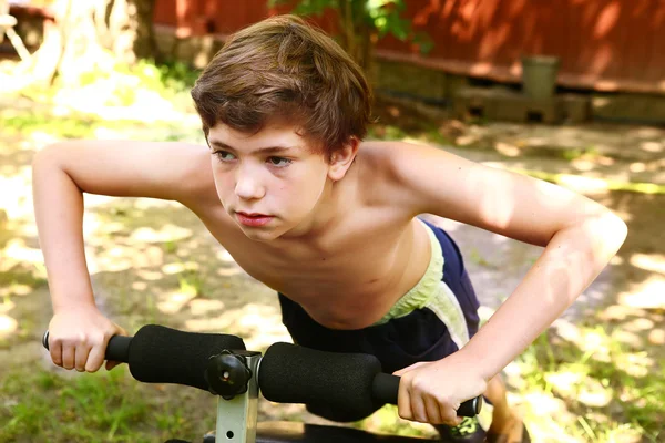 Pojke göra push upp bärbara tränare — Stockfoto