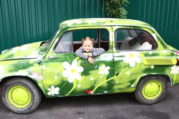 Blond smiling preteen girl in old painted car — Stock Photo, Image