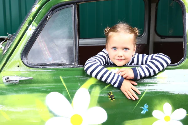 Blond lachende preteen meisje in de oude geschilderde auto — Stockfoto