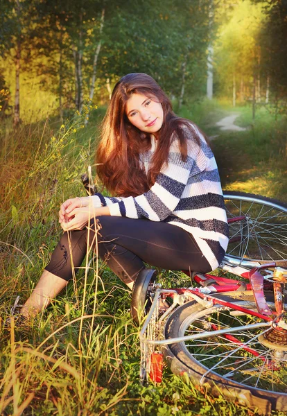 緩やかな長い茶色の髪の少女が自転車の上に座る — ストック写真