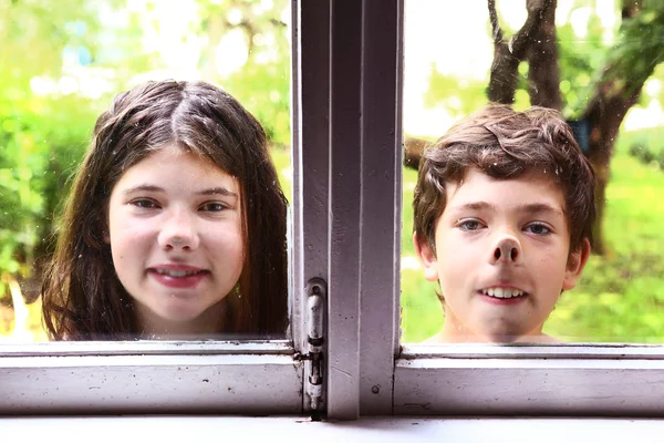 Mädchen und Junge mit Nase gegen Fenster gedrückt — Stockfoto