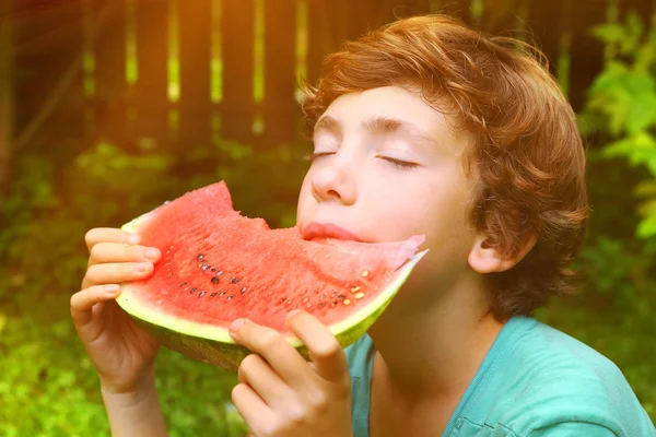 Preteen pojke bita vatten melon slice — Stockfoto