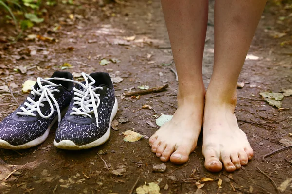 Bare feet and shoes on forest path — Stock Photo, Image