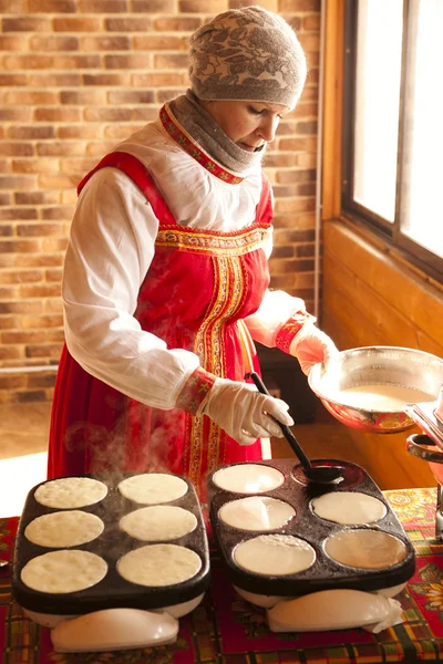 Frau in Volkstracht kocht Pfannkuchen — Stockfoto