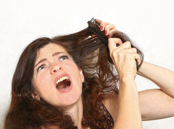Pretty young woman with brush comb stuck in hair — Stock Photo, Image