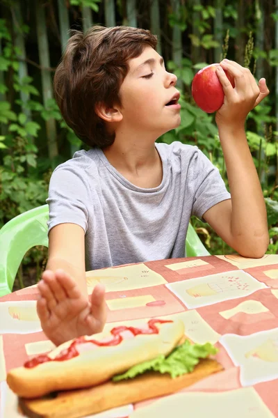 Knappe jongen eten apple weigeren hotdog — Stockfoto