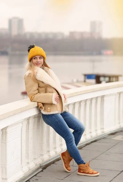 Fille blonde en tricot chapeau et manteau avec feuille d'érable gros plan portrait sur fond d'architecture de la ville — Photo