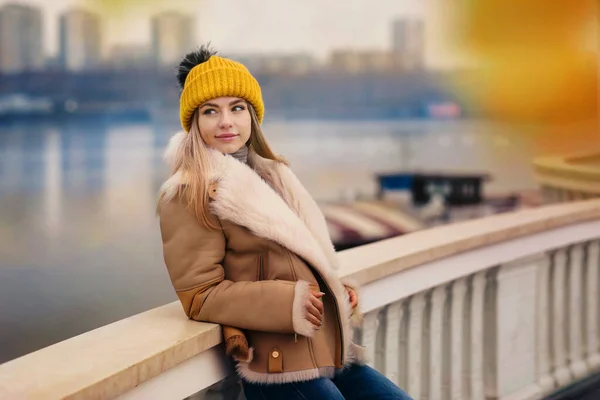 Fille blonde en tricot chapeau et manteau avec feuille d'érable gros plan portrait sur fond d'architecture de la ville — Photo