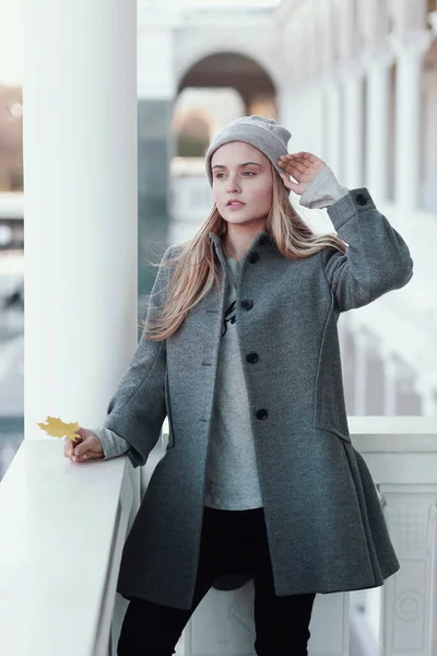 Fille blonde en tricot chapeau et manteau avec feuille d'érable gros plan portrait sur fond d'architecture de la ville — Photo