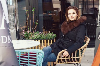  Fox Dawn ceketli sarışın iş kadını. Kapüşonlu, açık hava kafesinin arka planında yakın plan fotoğrafı var.