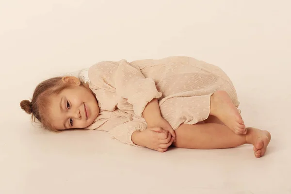 Cute little blond baby girl in ivory color dress full body portrait — Stock Photo, Image