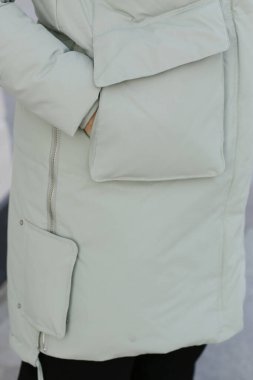 Beyaz önlüklü, cebinde detay olan ve manken elleri olan beyaz ceketin fotoğrafını çek. Şehir arka planındaki fotoğrafı kapat.