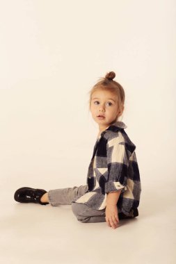 Siyah çizmeli, kotlu, kareli gömlekli, beyaz renkli, şirin sarışın kız.