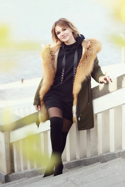 Blond business woman in fox fir dawn jacket with hood closeup photo on city park background — Stock Photo, Image