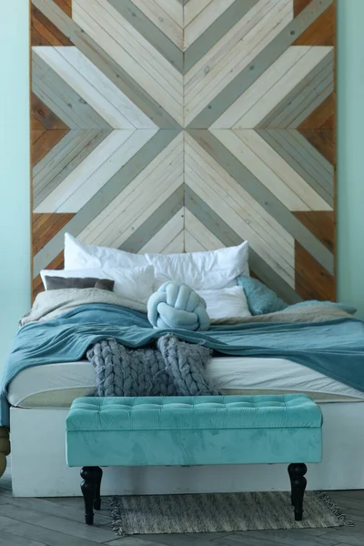 Bedroom corner blue bad, knitted rag, pillows and bench close up photo — Stock Photo, Image