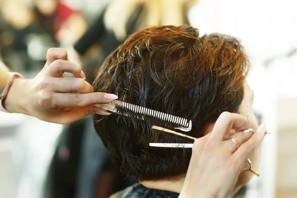 hairdresser hand with scissors making haircut and hair dye on client closeup photo