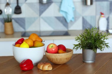 Tabaktaki meyveler ot bitkisi, kırmızı biber ve kruvasan ile mavi mutfak arka planında yakın plan fotoğrafı