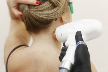 Kozmetik uzmanları kadın boynundaki lazer tüy temizleme prosedürünü uygular.