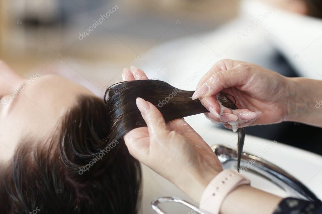 hairdresser hand washing hair on client close up photo in hair salon