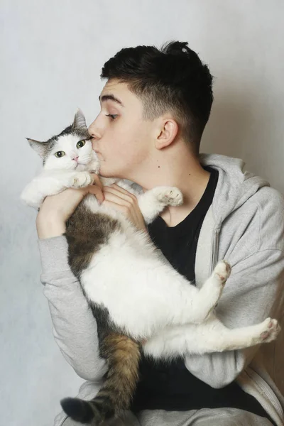 Genç çocuk kediye sarılıyor. Yakından çekilmiş beyaz bir fotoğraf. — Stok fotoğraf