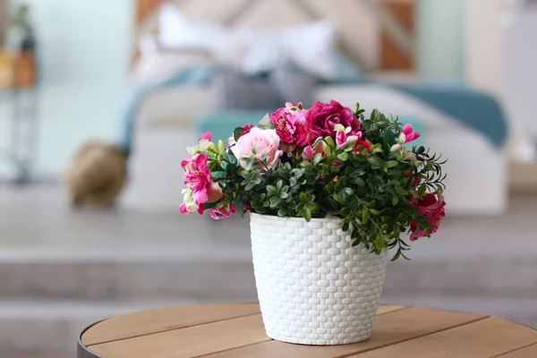 Modern bedroom closeup fragment with flowers in vase, sofa and pillows on background — Stock Photo, Image