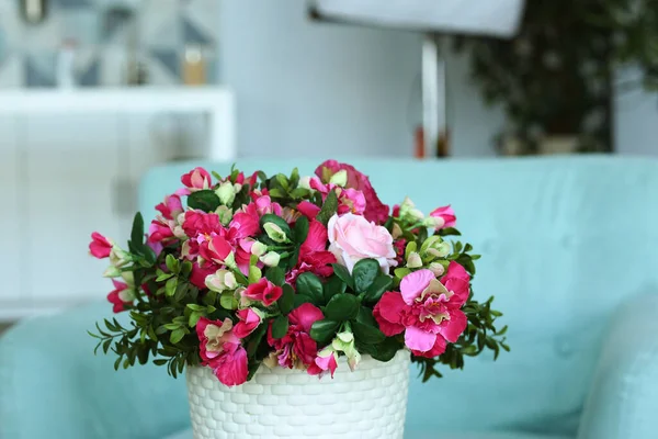 Modern bedroom closeup fragment with flowers in vase, sofa and pillows on background — Stock Photo, Image