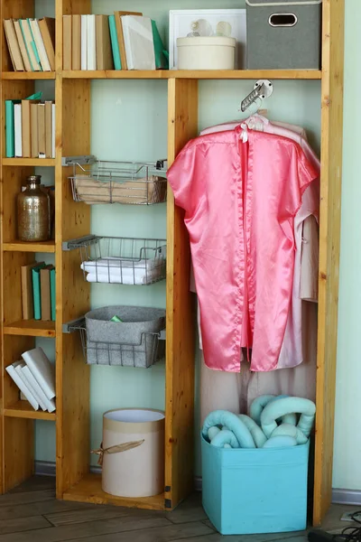 bedroom corner with open wardrobe and pink robe hanging closeup photo