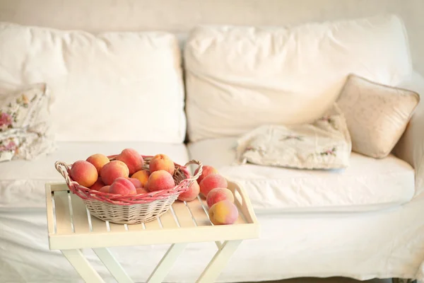 Coin confortable de chambre blanche avec canapé, table et panier de peac — Photo