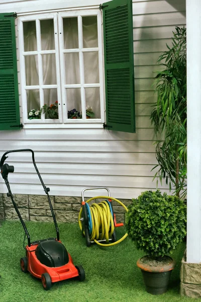 Beautiful exterior fragment of mansion house with window and hose and lawn mower — Stock Photo, Image