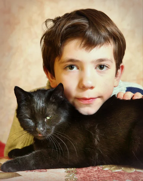 Bonito preteen menino com preto gato na mesa — Fotografia de Stock