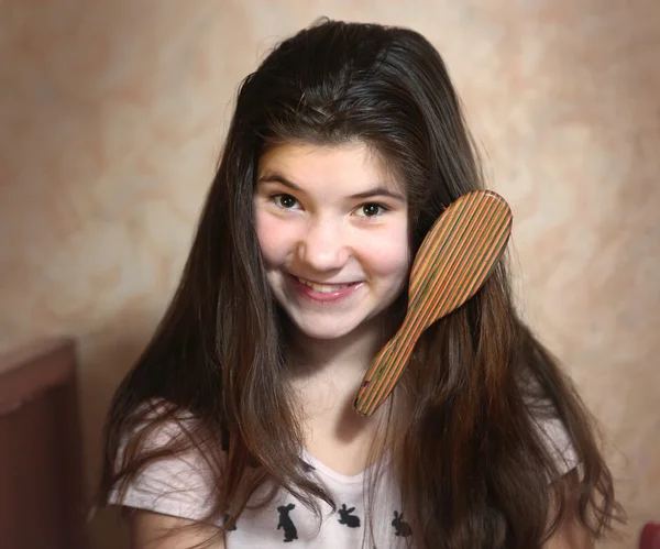 Beautiful teen girl try to comb her long dark thick hair — Stock Photo, Image