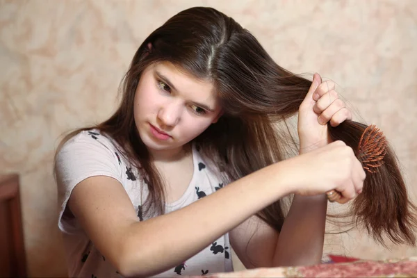 Beautiful teen girl try to comb her long  thick hair — Stock Photo, Image