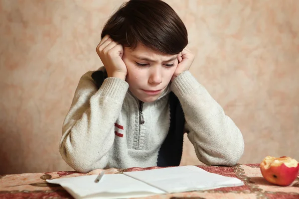 Kleiner preteen boy tun seine Hausaufgaben hat Schwierigkeiten Stockbild