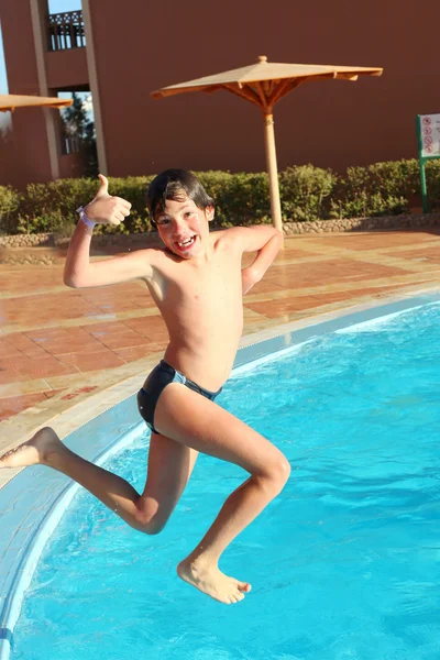 Preteen boy jump into the open air swimming pool — Stock Photo, Image