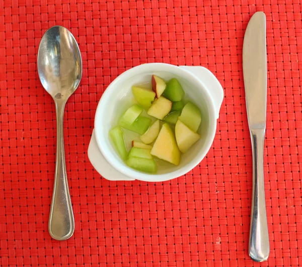 Fruitsalade op de rode mat met mes en lepel — Stockfoto