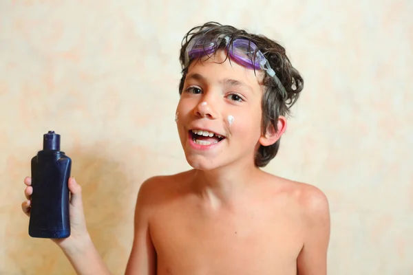 Knappe lachende preteen jongen met anti zonnebrand room — Stockfoto