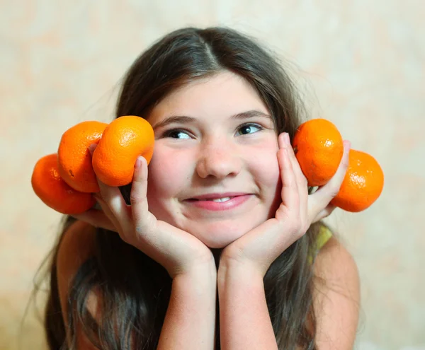 Pretty teenager girl with long dark hair hold tangerines — Stock Photo, Image