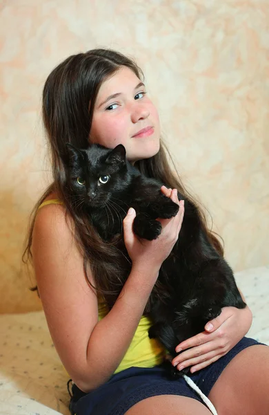 Preteen mooi meisje met donkere lange haren houden zwarte kat — Stockfoto