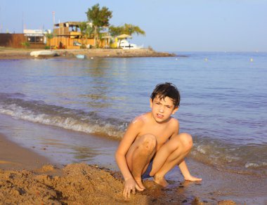 preteen handsome boy swimming on the red sea beach and yaht back
