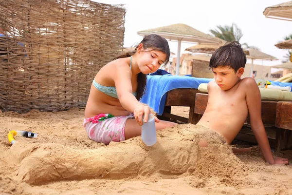 Hermanos preadolescentes hermano y hermana se divierten en juego de playa de arena —  Fotos de Stock