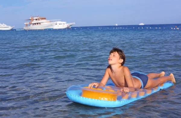 Menino bonito em maiô com colchão inflável no blu — Fotografia de Stock