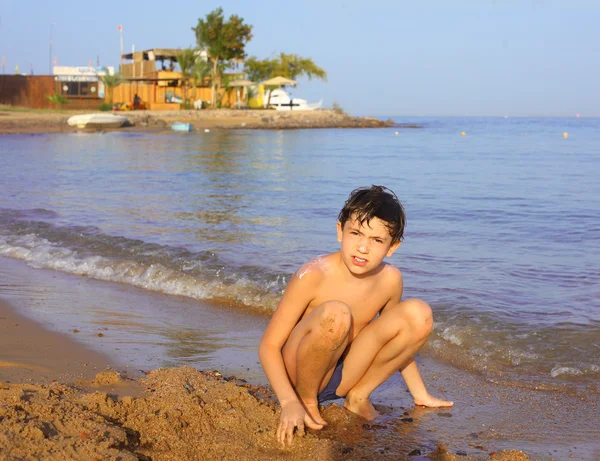 Preteen handsome boy swimming on the red sea beach and yaht back — Stok fotoğraf