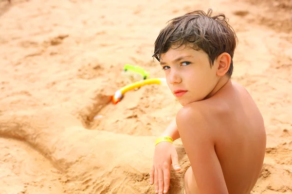 Preteen bonito menino na areia escultura de sereia cauda com — Fotografia de Stock