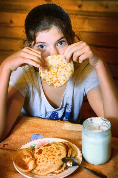 Mooie tiener meisje met pannenkoeken in het land keuken backgro — Stockfoto