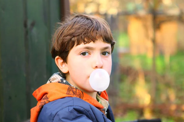 Preteen handsome boy with chewing gum bubble close up counrty po — Stock Photo, Image