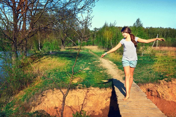 Genç güzel kız ülkeleri üzerinde ahşap brich üzerinde yürüyüş — Stok fotoğraf