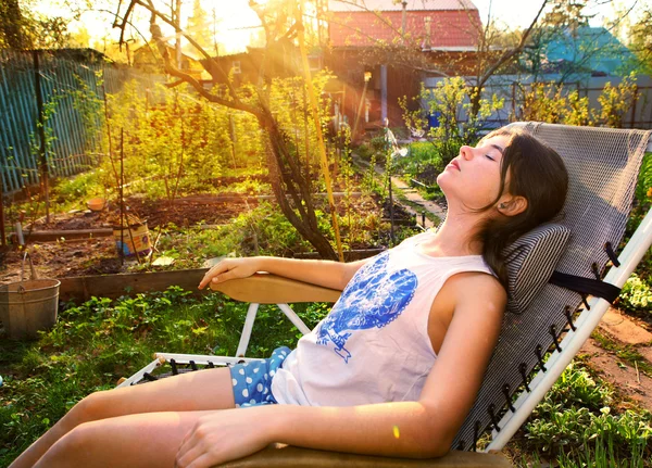 Adolescente hermosa chica yacía en chaise longue bajo el sol puesta del sol en — Foto de Stock